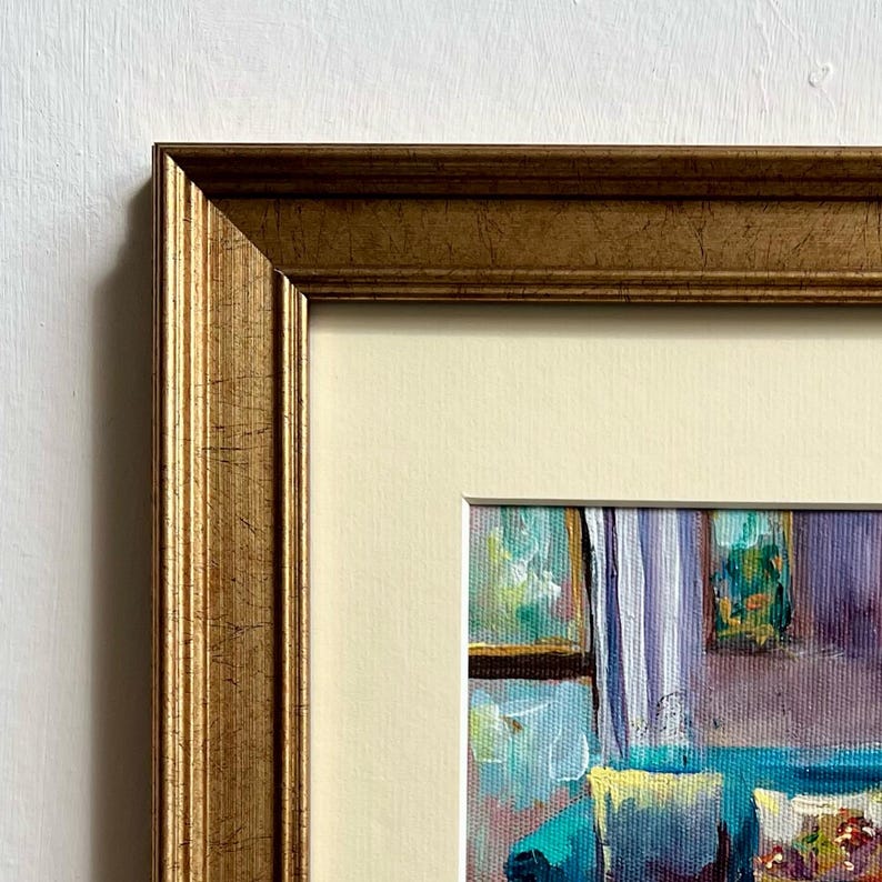 May include: A framed painting with a gold-colored ornate frame. The painting depicts an interior scene with a sofa, curtains, and other decorative elements. The artwork is in a colorful, impressionistic style.