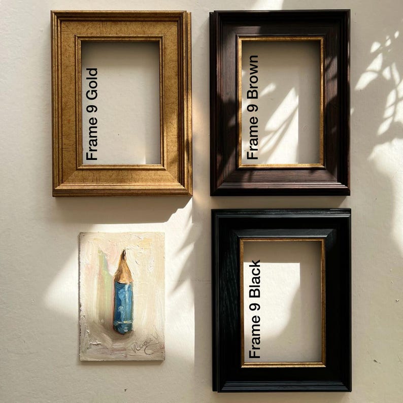 Puede incluir: Cuatro marcos de fotos rectangulares en oro, marr&oacute;n y negro, con el texto "Frame 9 Gold", "Frame 9 Brown" y "Frame 9 Black". Tambi&eacute;n se ve una peque&ntilde;a pintura de un l&aacute;piz azul.
