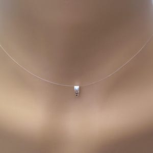 Może przedstawiać: Przezroczysty, niewidoczny naszyjnik ze srebrnym zawieszką. Naszyjnik znajduje się na szyi manekina.
