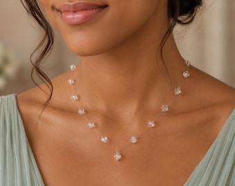 May include: A delicate necklace featuring a thin, transparent nylon cord adorned with multiple small, clear, faceted crystal beads spaced evenly along the length, culminating in a single centered crystal drop pendant.