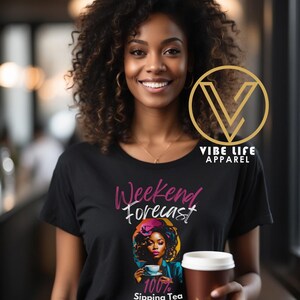 May include: Black t-shirt with a graphic of a woman sipping tea and the text "Weekend Forecast 100% Sipping Tea & Minding My Business". The graphic is in a colorful style with a pink, blue, and yellow color scheme. The text is in pink and white.