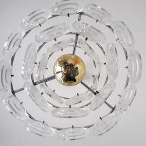 May include: A modern chandelier with a circular design featuring multiple clear glass rings. The chandelier has a gold-colored center piece.