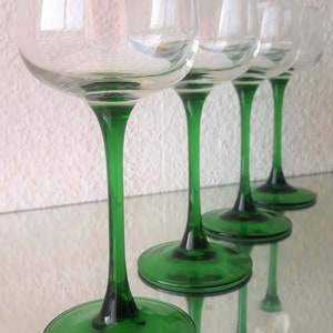K&ouml;nnte beinhalten: Vier klare Weingl&auml;ser aus Glas mit gr&uuml;nen Stielen und F&uuml;&szlig;en. Die Gl&auml;ser sind in einer Reihe angeordnet, wobei die F&uuml;&szlig;e der Gl&auml;ser dem Betrachter immer n&auml;her kommen.