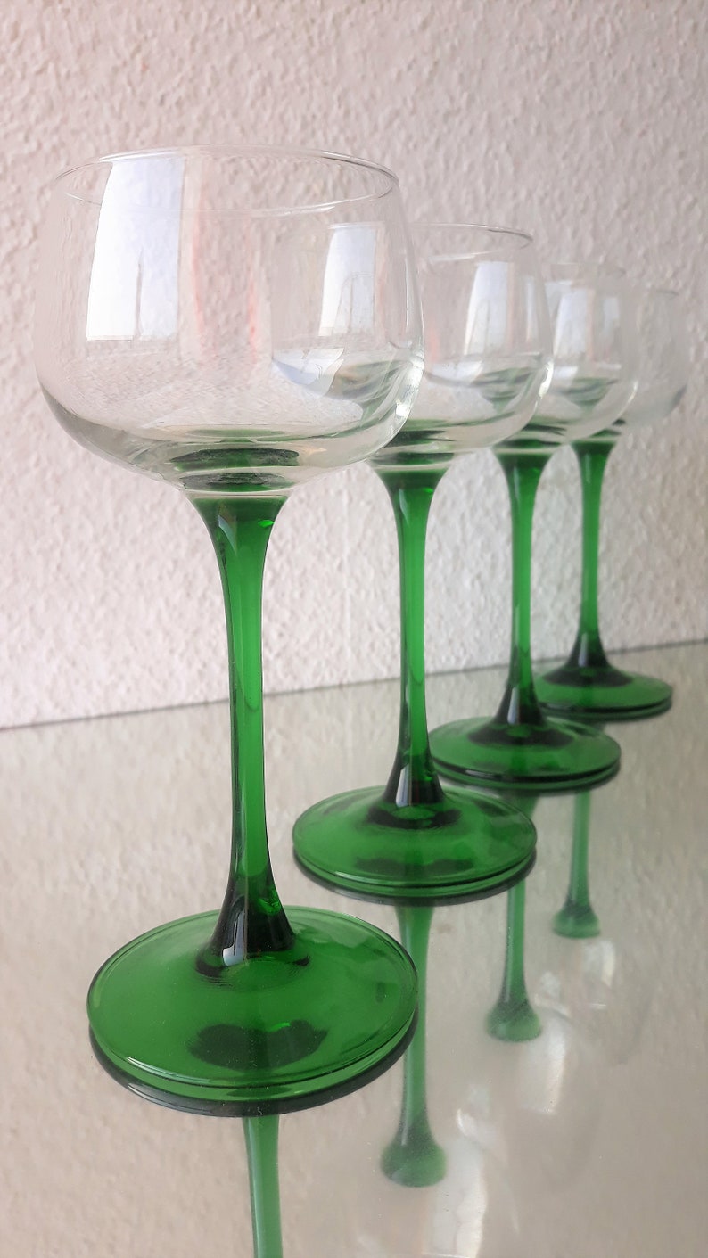 K&ouml;nnte beinhalten: Vier klare Weingl&auml;ser aus Glas mit gr&uuml;nen Stielen und F&uuml;&szlig;en. Die Gl&auml;ser sind in einer Reihe angeordnet, wobei die F&uuml;&szlig;e der Gl&auml;ser dem Betrachter immer n&auml;her kommen.