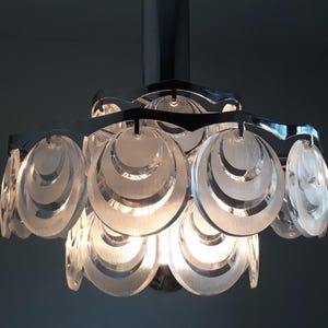 May include: A chrome and clear glass ceiling light fixture with a modern design. The light fixture has multiple layers of clear glass circles.