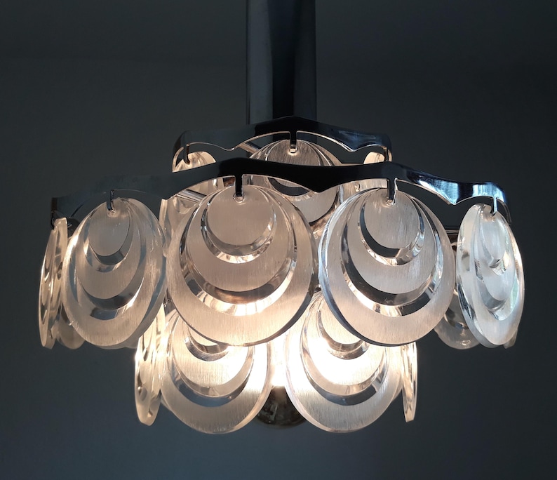 May include: A chrome and clear glass ceiling light fixture with a modern design. The light fixture has multiple layers of clear glass circles.