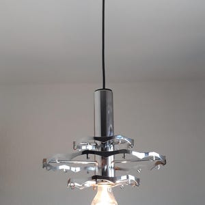 May include: A chrome pendant light fixture with a circular design and a single light bulb.