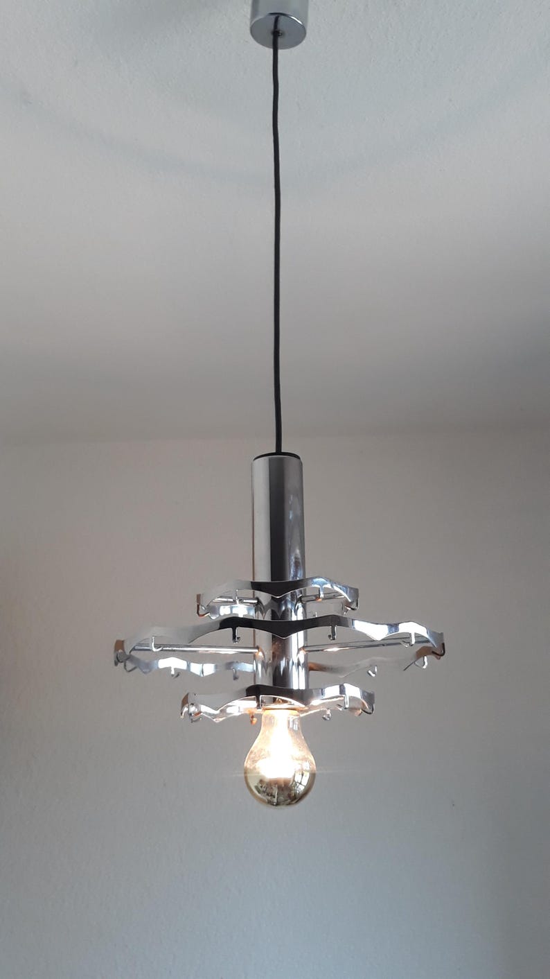 May include: A chrome pendant light fixture with a circular design and a single light bulb.