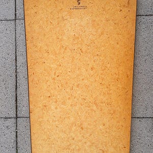 May include: A rectangular wooden framed mirror with a decorative metal top. The mirror's backing is a light brown color with a textured surface. The text "UNCHNER ZIERSPIEGEL" is visible on the back.