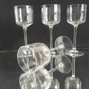 Könnte beinhalten: Vier klare Weingläser aus Glas mit einem dekorativen, geätzten Design. Die Gläser sind in einer Gruppe angeordnet, wobei ein Glas auf der Seite liegt.