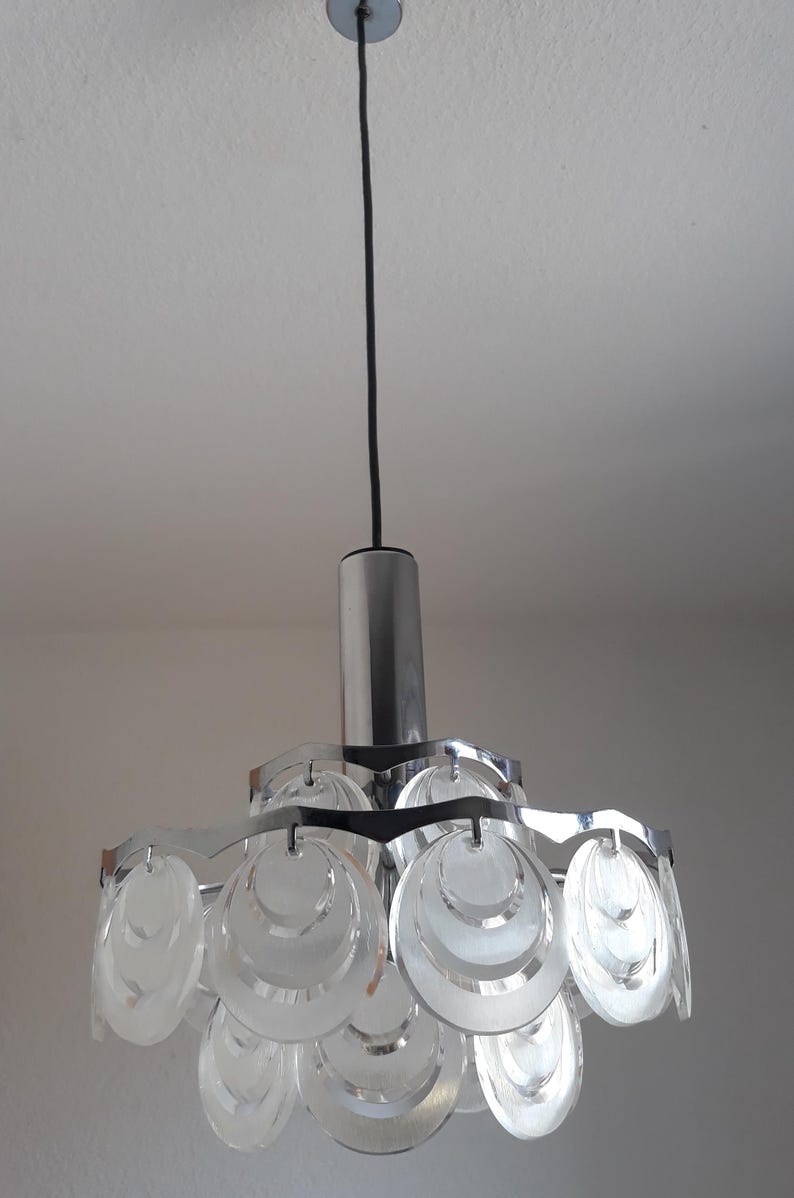 May include: A chrome and glass pendant light fixture with a circular design. The light fixture has multiple layers of clear glass circles that are stacked on top of each other.