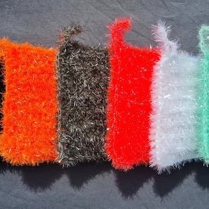 Pode incluir: Seis esfregões de cozinha coloridos com uma alça de laço. Os esfregões são feitos de um material felpudo e texturizado e são nas cores preto, laranja, cinza, vermelho, branco e verde.