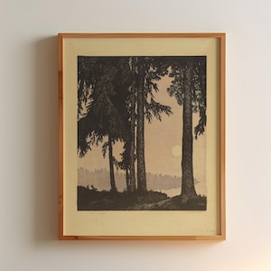 May include: A framed black and white landscape print depicting trees near a body of water. The artwork is in a light-colored wooden frame and hangs on a white wall. A small wooden side table with a lamp is next to a bed.