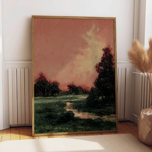Puede incluir: Pintura de paisaje enmarcada con una paleta de colores cálidos. La obra representa un campo con un camino que conduce a una línea de árboles oscuros bajo un cielo rosa y amarillo. El marco es de color marrón claro.
