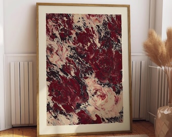 Op de afbeelding: Abstracte kunstafdruk in een houten lijst. Het kunstwerk toont een wervelend patroon van rode, zwarte en crèmekleurige kleuren. De ingelijste kunst leunt tegen een witte muur en een beige tapijt.