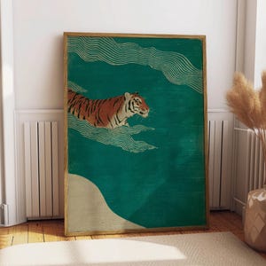 May include: A framed art print featuring a tiger swimming in a teal-colored sea. The tiger has orange and black stripes. The artwork has a vintage aesthetic with gold-colored wave patterns and a beige-colored land mass.