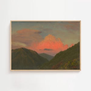 Puede incluir: Una pintura de paisaje enmarcada representa una cordillera bajo un cielo al atardecer. El cielo transita del azul al rosa, con una gran y vibrante formación de nubes rosas. Las montañas son verdes y el marco es de color madera clara.