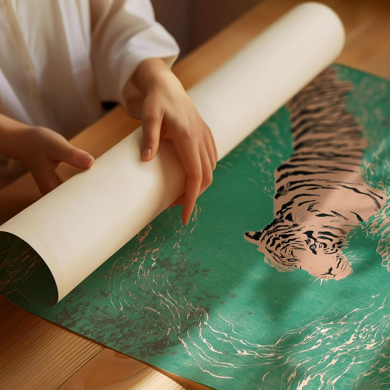 以下が含まれることがあります： 緑色の背景に虎のイラストが描かれたポスターが丸められています。虎はピンクと黒で描かれ、水のようなデザインが施されています。ポスターは木製のテーブルの上で広げられています。