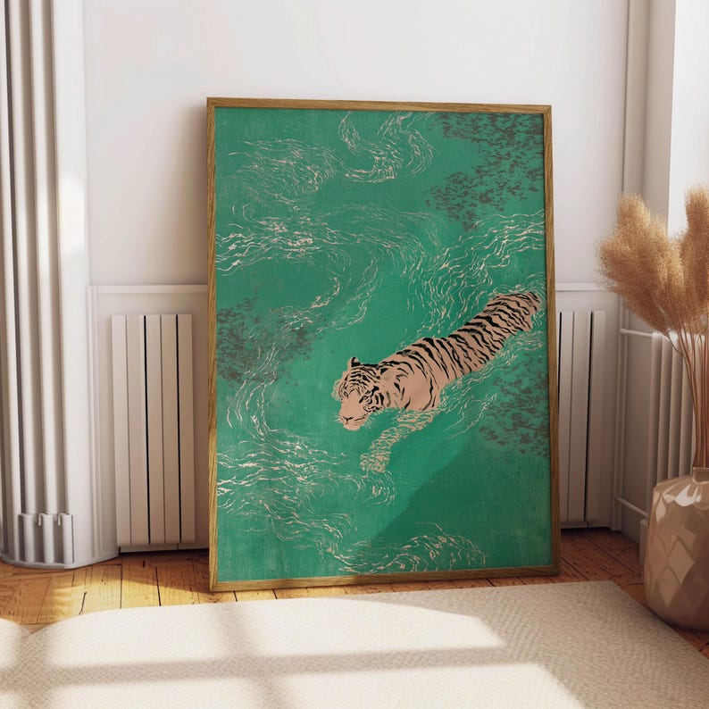 以下が含まれることがあります： 水色の水の中を泳ぐトラを描いた、額装されたアートプリント。トラは黒い縞模様とタン色の体をしている。水面には白い渦と濃い灰色の斑点がある。フレームは明るい茶色です。