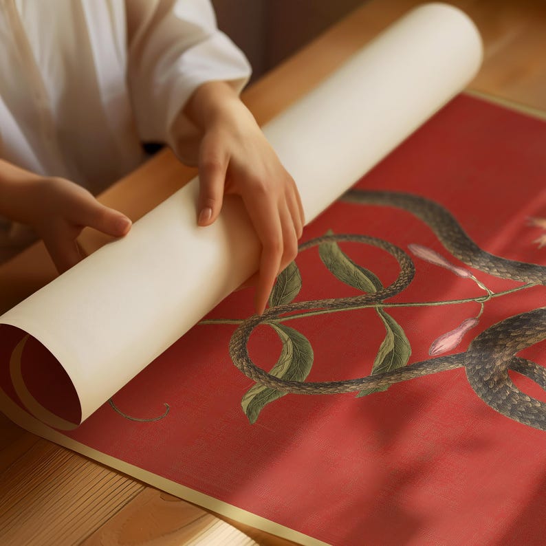 May include: A person is rolling up a red and green botanical print with a snake design. The print is on a white background.