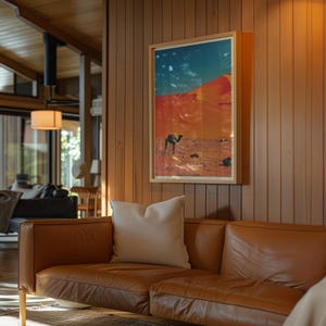K&ouml;nnte beinhalten: Ein braunes Ledersofa mit zwei wei&szlig;en Kissen vor einer Holzvert&auml;felung. An der Wand h&auml;ngt ein gerahmtes Bild eines Kamels, das durch eine W&uuml;stenlandschaft geht.