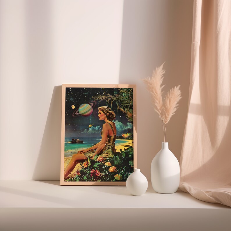 May include: A framed print of a woman sitting on a beach with a planet in the background. The woman is wearing a light blue dress and has long brown hair. The planet is a vibrant blue and purple with rings. The print is set against a white wall with a vase of dried flowers in the foreground.