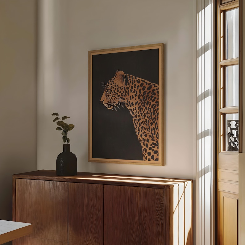 May include: A framed print of a leopard with a dark background. The leopard is facing to the left and has a brown and black spotted pattern.