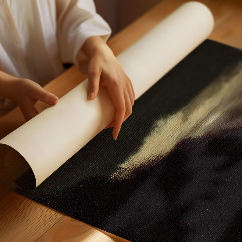 以下が含まれることがあります： 人が白黒のキャンバスプリントを展開しています。プリントは、薄い黄色と白の背景に人物の絵が描かれています。