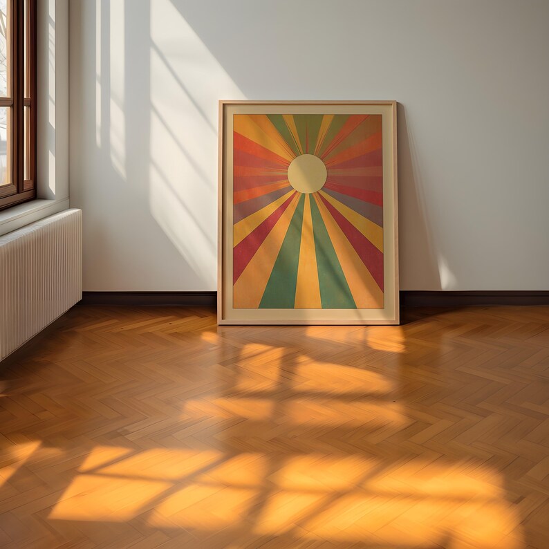 Op de afbeelding: Een ingelijste print van een kleurrijk zonnestralenontwerp met een witte cirkel in het midden. De zonnestralen zijn gemaakt van rode, oranje, gele, groene, blauwe en paarse strepen.