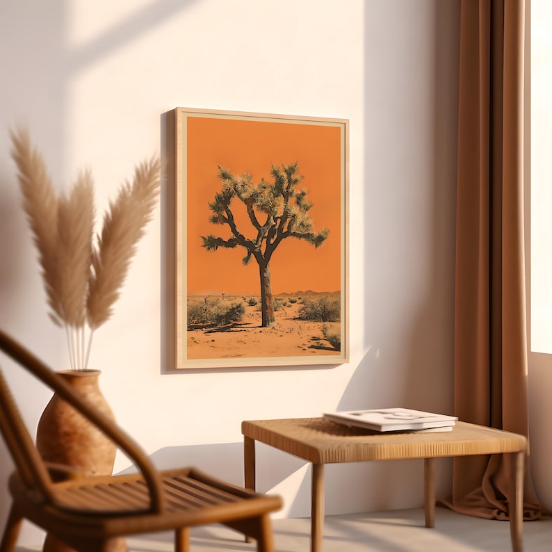 May include: A framed print of a Joshua tree in a desert landscape. The tree is silhouetted against a bright orange sky. The print is in a wooden frame.