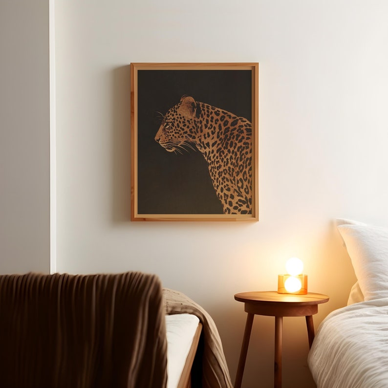 May include: A framed print of a leopard in a profile view, with a dark background. The leopard is a golden brown color with black spots. The frame is a light wood color.