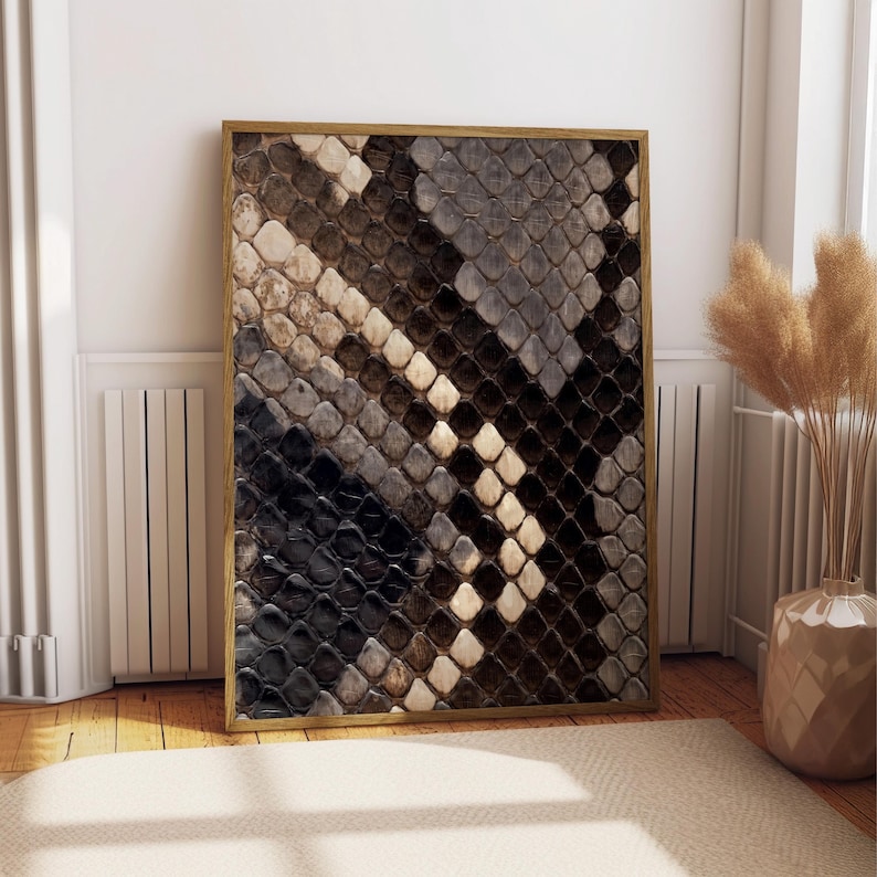 Op de afbeelding: Een rechthoekige wandkunstprint met een gedetailleerd, contrastrijk patroon van overlappende slangenschubben in tinten zwart, donkerbruin, cr&egrave;me en grijs, gevat in een dunne, lichtgekleurde houten lijst met een strakke rand.