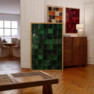 May include: A modern interior featuring framed art pieces. A large, framed artwork with a green, textured, square pattern is the focal point. Other framed pieces display red and orange square patterns. A wooden cabinet and table are also visible.