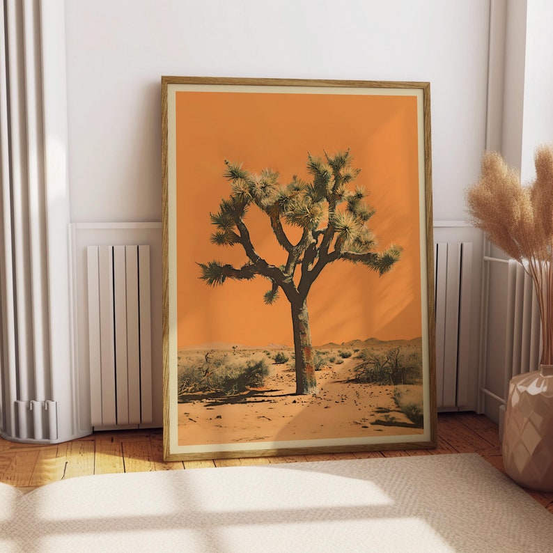 May include: A framed print of a Joshua tree in a desert landscape. The tree is silhouetted against a bright orange sky. The print is in a wooden frame.