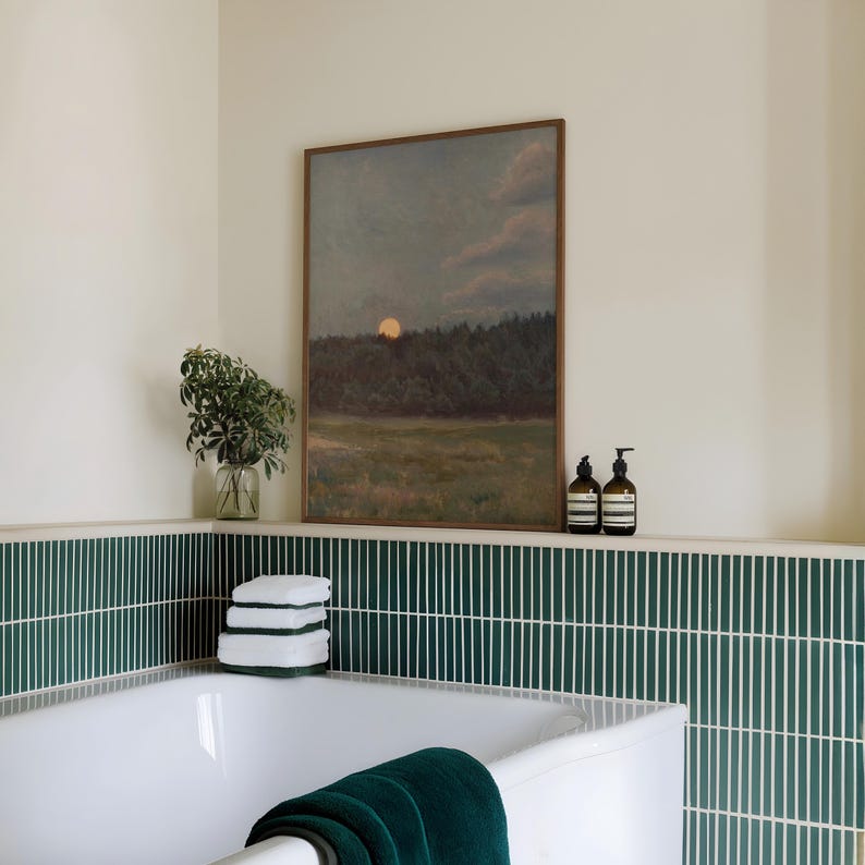 Puede incluir: Un rinc&oacute;n de ba&ntilde;o con una pintura de paisaje enmarcada. El espacio incluye una ba&ntilde;era blanca, toallas verdes y una pila de toallas blancas. Azulejos verdes verticales decoran la pared.