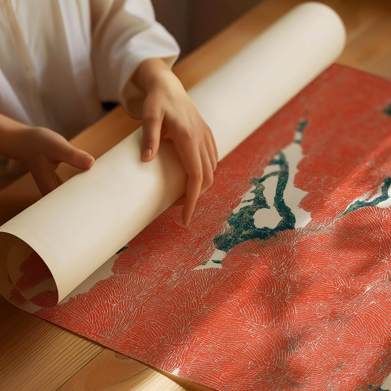 May include: A rolled-up, off-white paper print being unrolled onto a red and white patterned surface. The print features a design with red and white floral patterns and green accents. The scene is set on a wooden table.