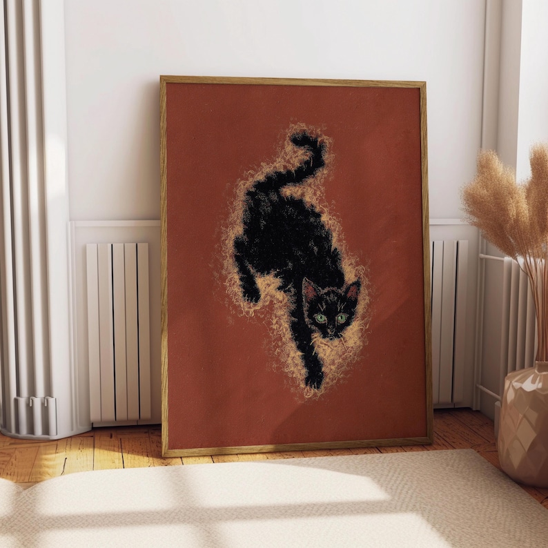 May include: A framed art print featuring a black cat with green eyes against a rust-colored background. The cat is depicted in a stylized, dynamic pose, surrounded by a golden, textured effect. The artwork is in a wooden frame.
