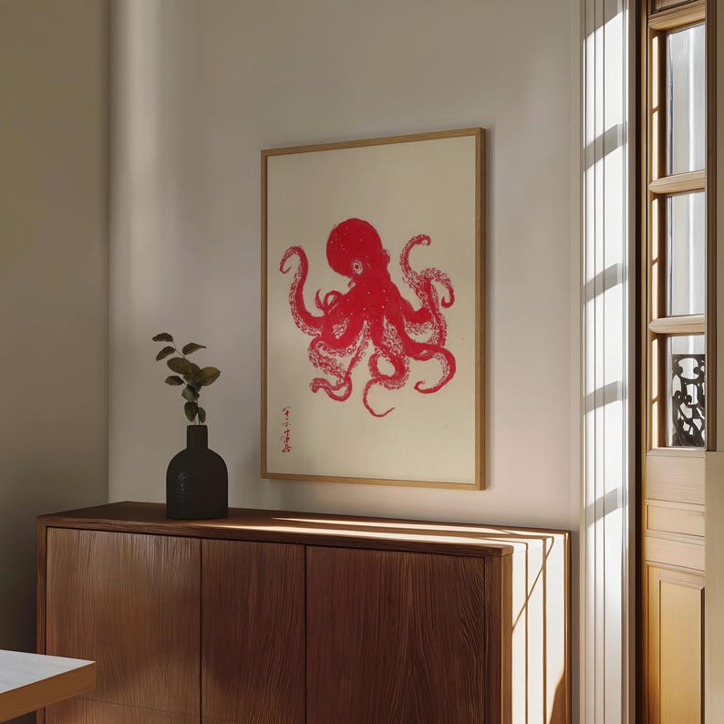 May include: A framed print featuring a red octopus illustration on a cream background. The artwork is in a wooden frame and hangs above a wooden cabinet. The octopus design has a Japanese aesthetic.