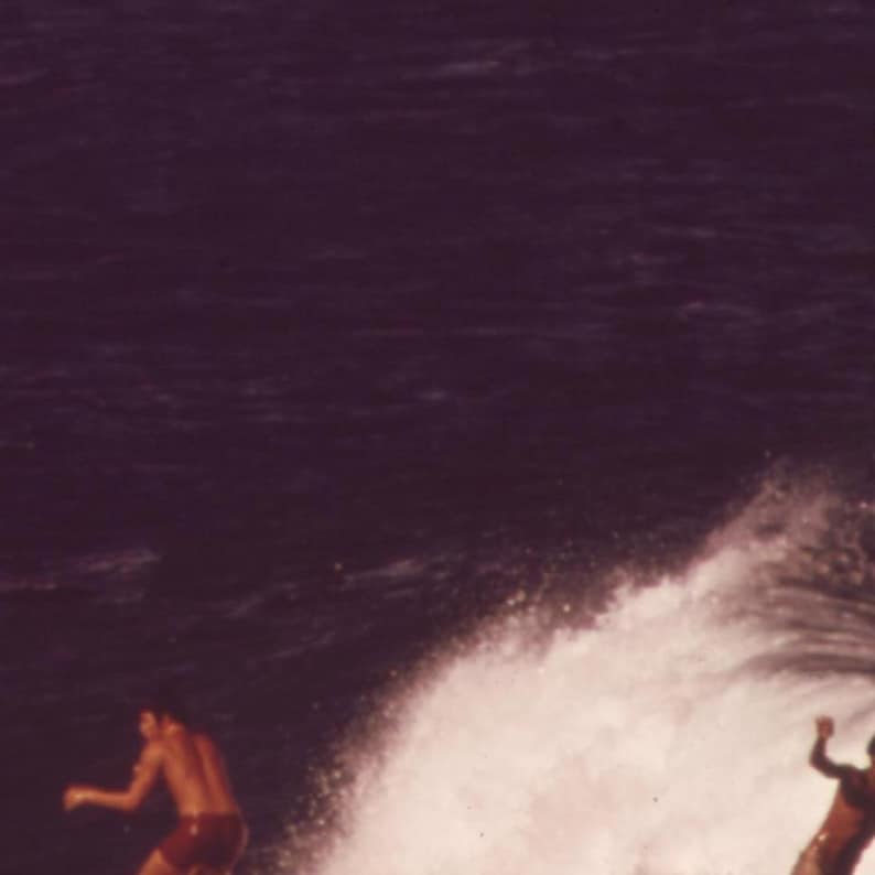 May include: Two people surfing on a wave. The wave is breaking and the water is white and foamy. The sky is dark blue.