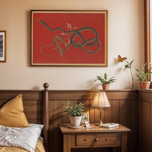 May include: A framed print of a black snake coiled around a vine with pink flowers on a red background. The print is hanging on a wall in a bedroom with a wooden headboard and nightstand.