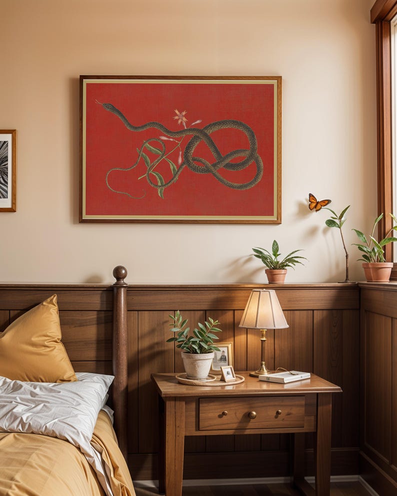 May include: A framed print of a black snake coiled around a vine with pink flowers on a red background. The print is hanging on a wall in a bedroom with a wooden headboard and nightstand.
