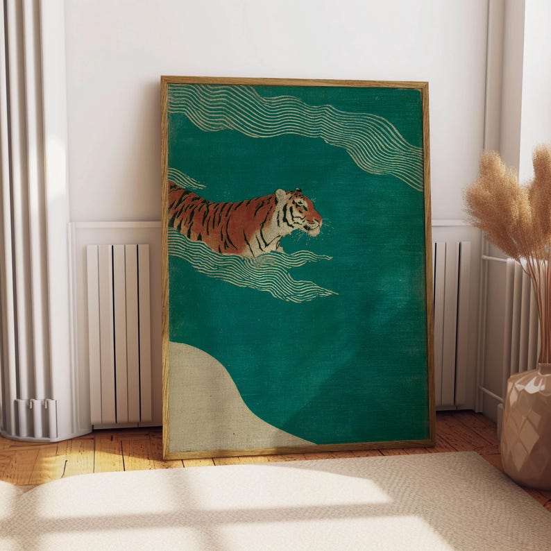 May include: A framed art print featuring a tiger swimming in a teal-colored sea. The tiger has orange and black stripes. The artwork has a vintage aesthetic with gold-colored wave patterns and a beige-colored land mass.