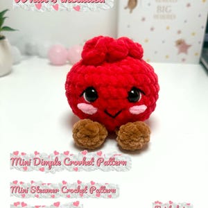 Puede incluir: Un juguete de peluche tejido a ganchillo rojo con cuerpo redondo, pies marrones, ojos de seguridad negros y mejillas rosadas. El texto incluye: What's included, Mini Dimple Crochet Pattern, Mini Steamer Crochet Pattern, Steamer Label, Finished size 8 cm/3.1 in.