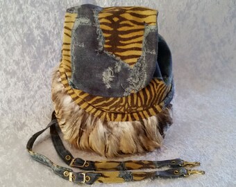 Può includere: Una piccola borsa rotonda con motivo marrone e blu con un bordo di pelliccia. La borsa ha una lunga tracolla regolabile in denim e pelle.