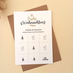 May include: A Christmas greeting card with the words "Frohe Weihnachten" in gold script. The card features a tic-tac-toe style game with Christmas trees and bunnies. The card is on a brown envelope.