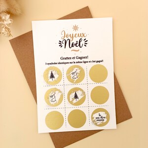 May include: A Christmas scratch card with the words "Joyeux No&euml;l" and "Grattez et Gagnez!" printed on it. The card features nine gold circles, some with Christmas tree and bunny illustrations. The card is on a brown envelope.