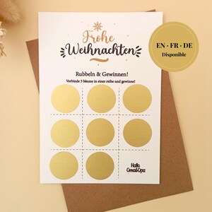 May include: A white scratch-off Christmas card with gold foil circles arranged in a tic-tac-toe grid. The card features the German text "Frohe Weihnachten" and "Rubbeln & Gewinnen!" with a brown envelope. A gold circle indicates availability in English, French, and German.