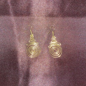 May include: A pair of gold wire earrings with a spiral design. The earrings are dangling and have a simple hook closure.