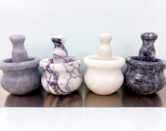 May include: Four marble mortar and pestle sets in different colors. Two are gray, one is white, and one is white with purple and gray marbling.