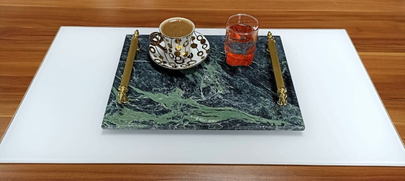 May include: A green marble serving tray with gold handles, a cup of coffee and a glass of orange juice.